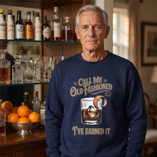 Senior man wearing navy sweatshirt at home bar with bottles and oranges