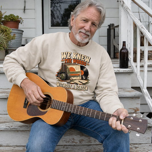 Beige vintage sweatshirt with printed slogan, worn by senior man playing guitar outdoors