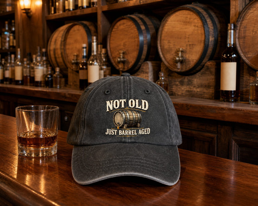 A long wooden tavern bar with the black cap and a glass of bourbon on it, barrel ends in the wall behind