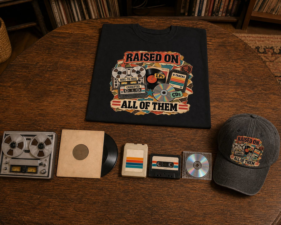 A reel-to-reel tape, a vinyl LP, an 8-track, a cassette and a CD lined up beside the black cap and tee