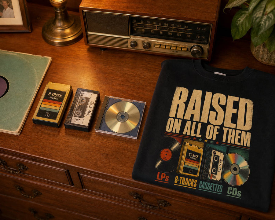 An LP, an 8-track, a cassette and a CD laid in a row beside the black sweatshirt