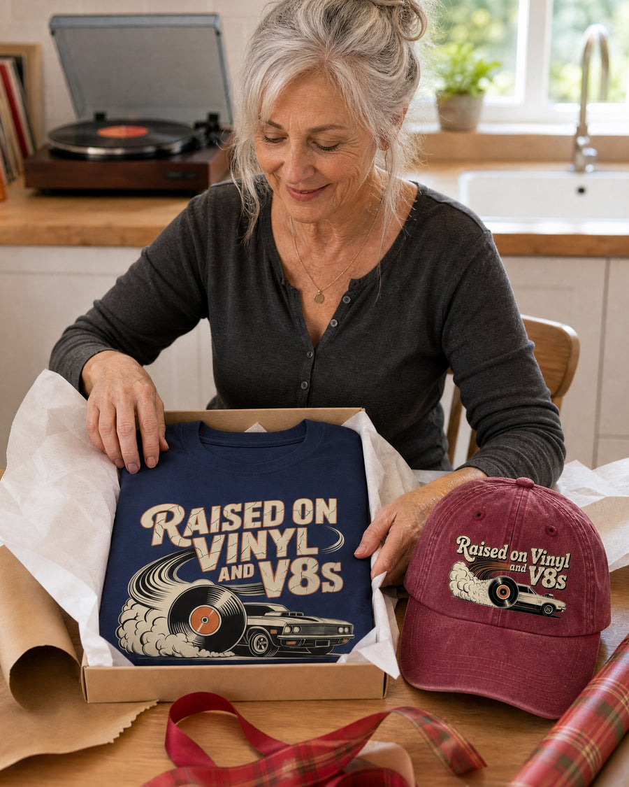 A woman wrapping the navy tee in a gift box with the wine red cap beside it