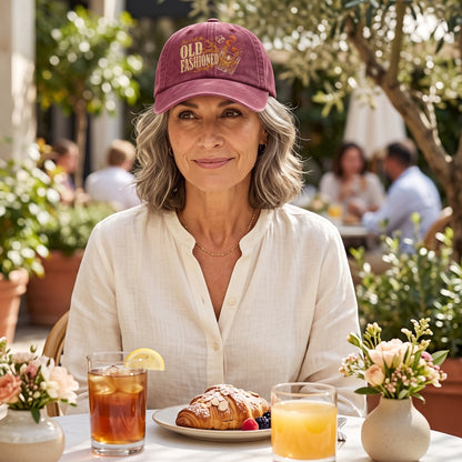Woman wearing burgundy cap at outdoor cafe with drinks and pastry