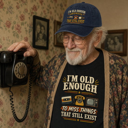 An elderly man wearing a navy blue graphic t-shirt and matching baseball cap, holding a vintage black rotary telephone in a retro-themed room with floral wallpaper.