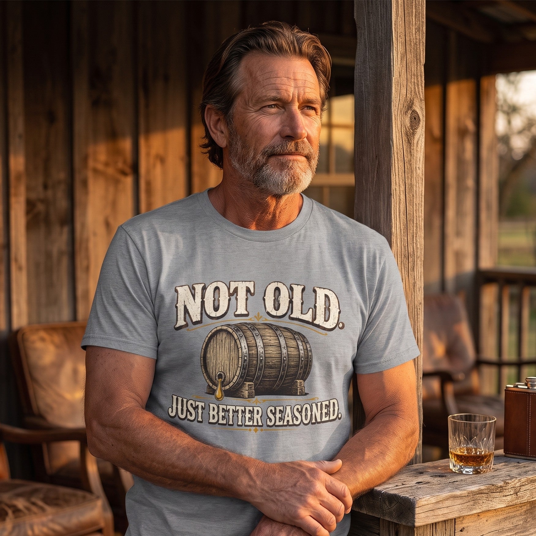 Man in gray T-shirt on porch beside whiskey glass and box