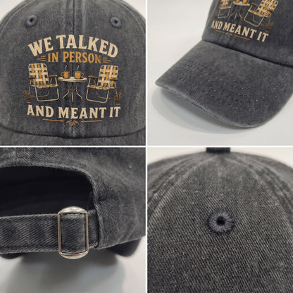 A dark gray acid-wash baseball cap shown in a four-panel collage, featuring embroidered text reading 'WE TALKED IN PERSON AND MEANT IT' with an outdoor chair-and-table graphic. The collage shows the front embroidery, side profile, adjustable strap with metal buckle, and button on the crown.