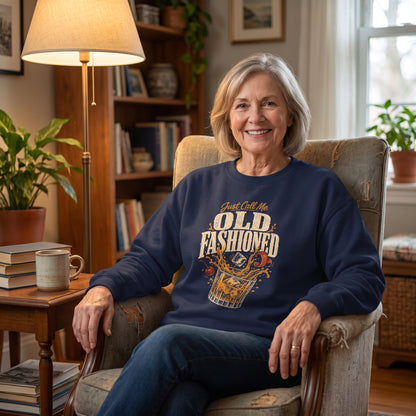 Woman in navy sweatshirt sitting by lamp, books, plant, and mug