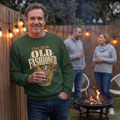 Man in forest green sweatshirt holding drink near backyard fire pit