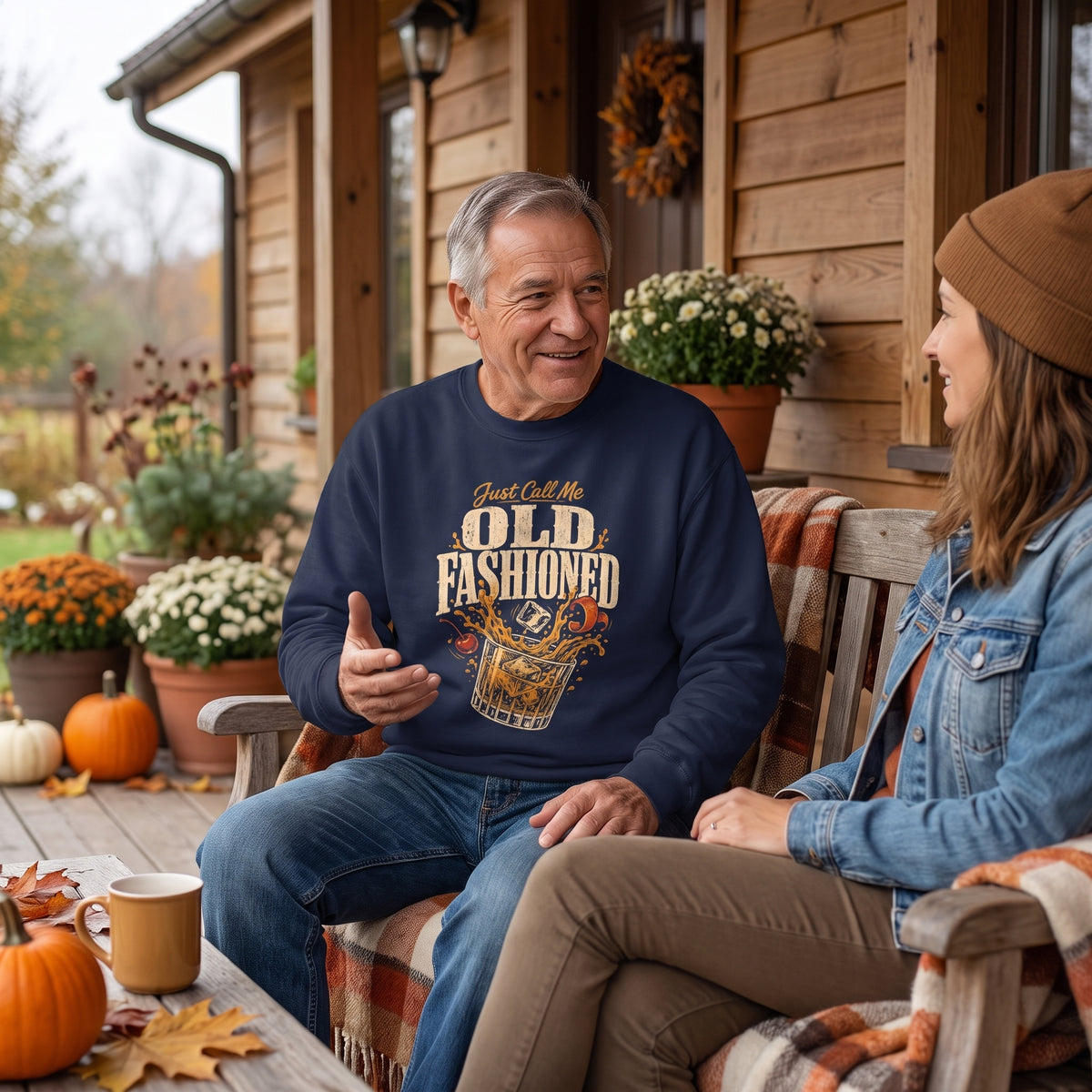 Man in navy sweatshirt chatting on porch among pumpkins and flowers