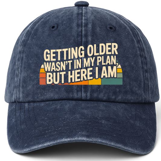 Navy vintage washed cap with “Getting Older Wasn’t in My Plan, But Here I Am.” Sunset Fade Reality Cap printed front design
