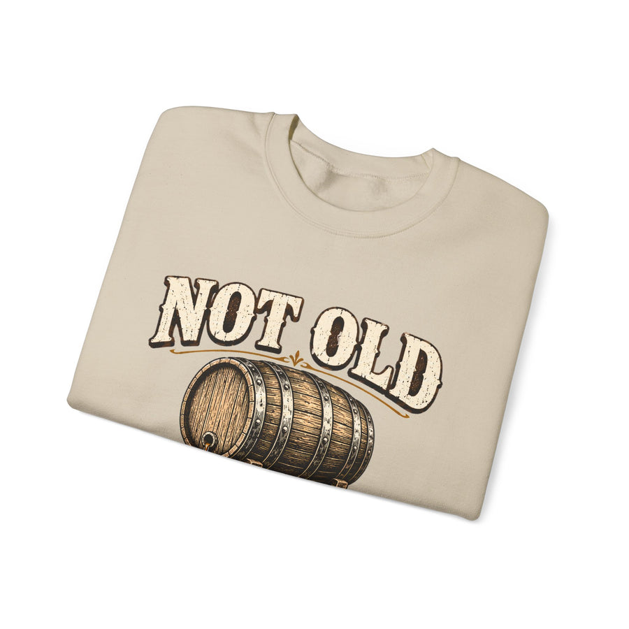 Folded cream sweatshirt showing barrel graphic and Not Old front print
