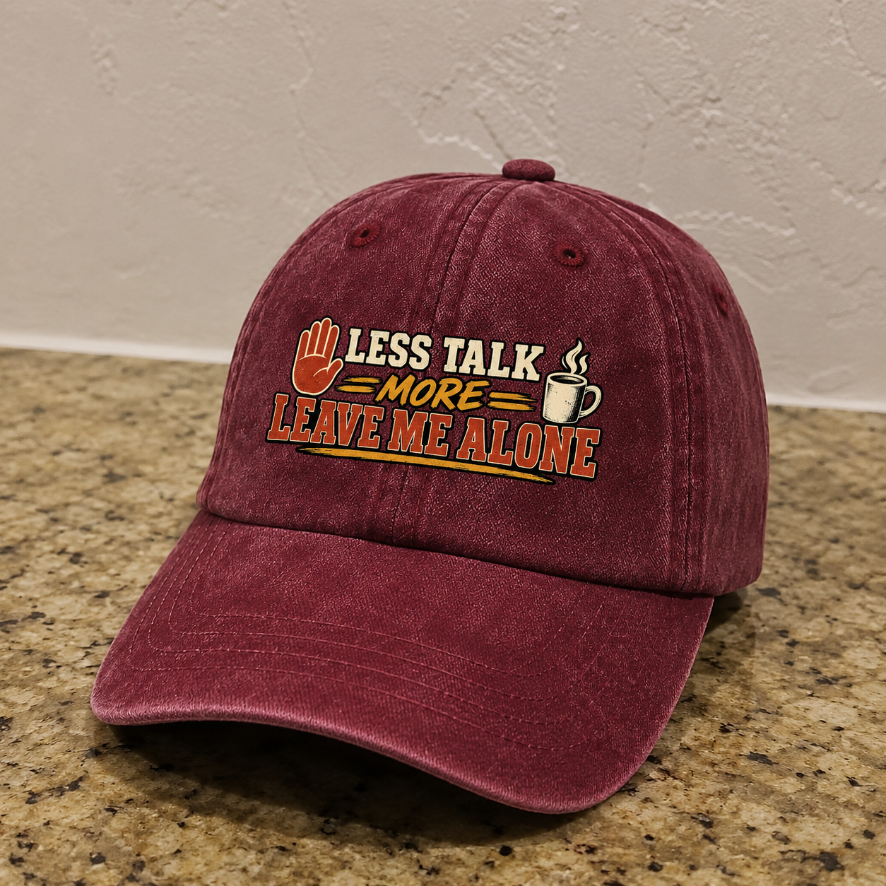 Burgundy vintage washed cap with printed “Less Talk More Leave Me Alone” slogan, angled view