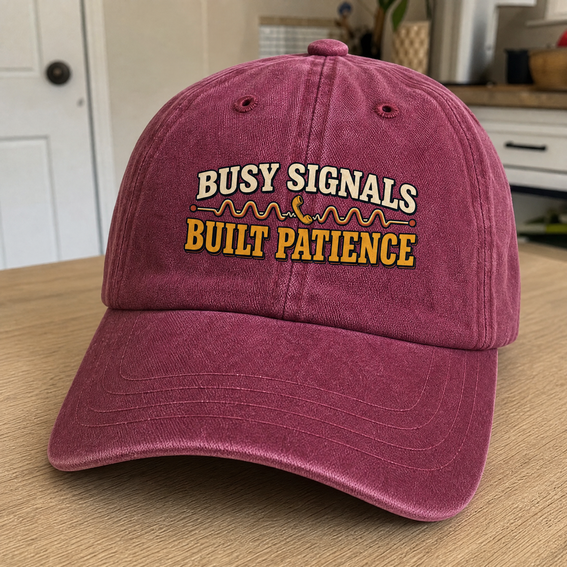 Burgundy vintage washed cap with printed “Busy Signals Built Patience” slogan, angled view.