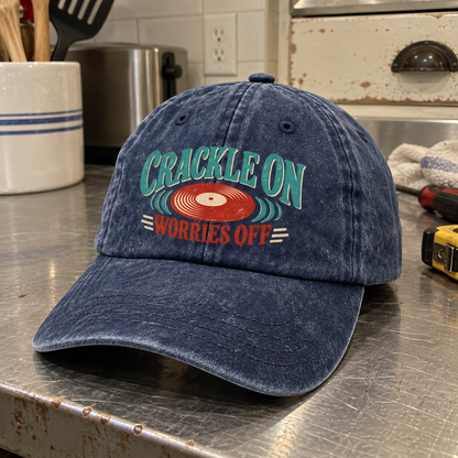 Angled view of navy vintage washed cap with printed Crackle On Worries Off record design