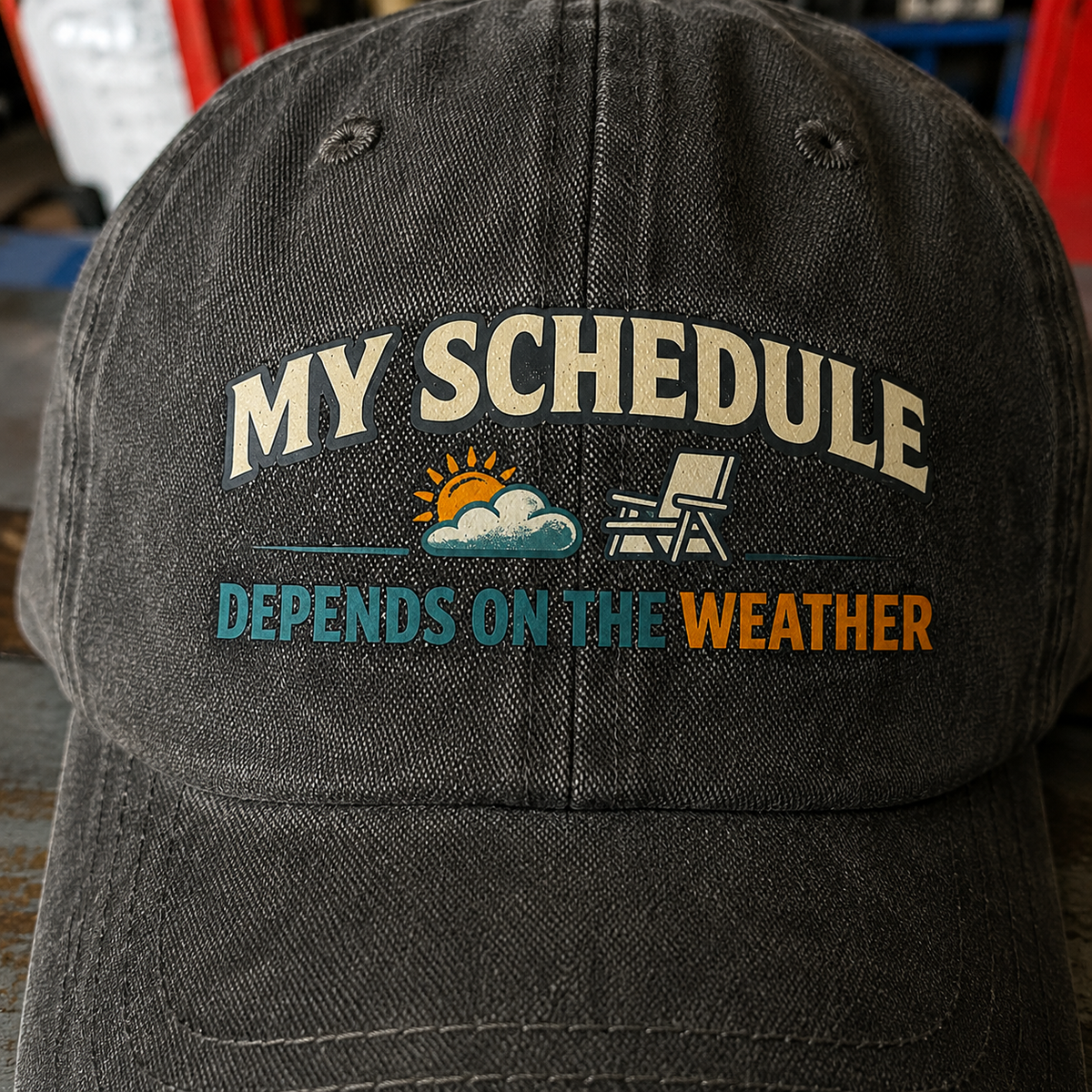 Black vintage washed cap with printed “My Schedule Depends On The Weather” slogan, front angle.