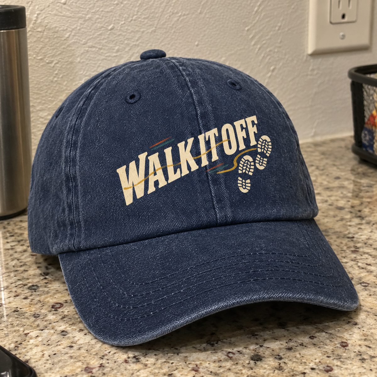 Navy vintage washed cap with printed Walk It Off slogan and footprint design, angled view