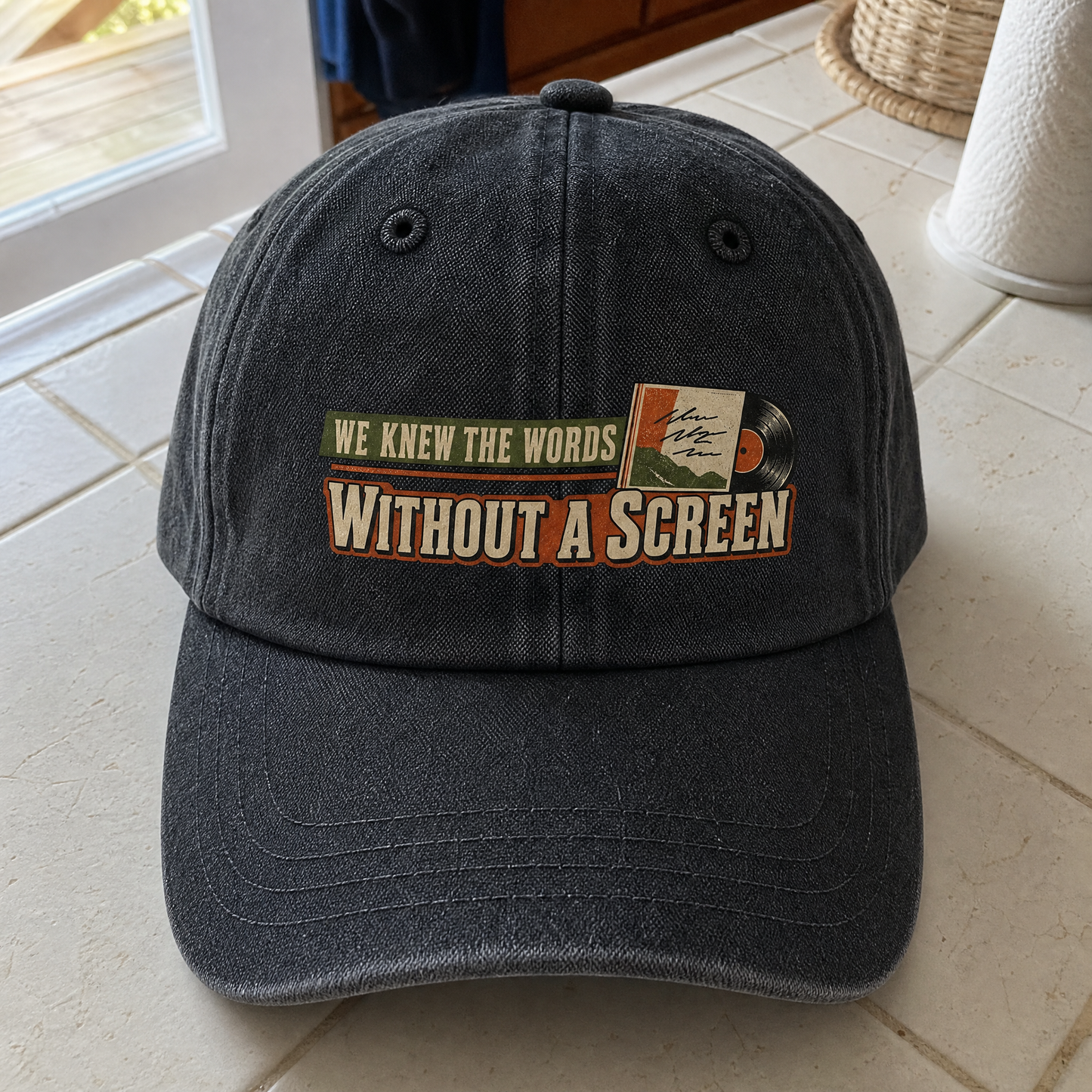 Black vintage washed cap with printed “We Knew the Words Without a Screen” slogan, angled.