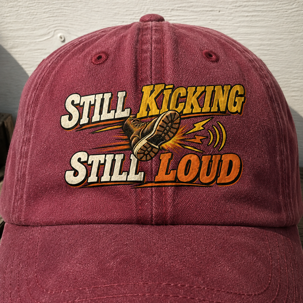 Vintage washed cap with printed Still Kicking Still Loud slogan, maroon front angle