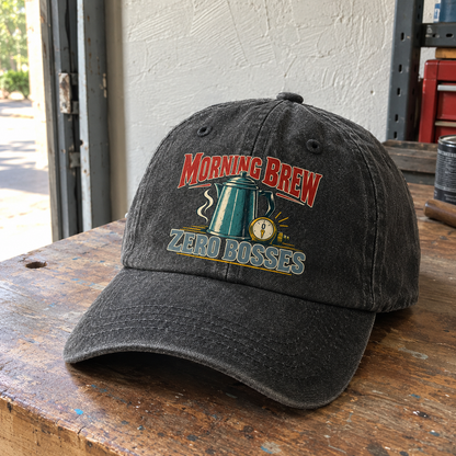 Black vintage washed cap with printed “Morning Brew Zero Bosses” slogan, shown at an angle on workbench