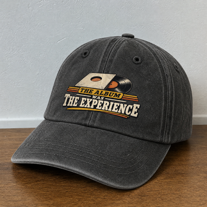 Black vintage washed cap with printed The Album Was The Experience design, angled view.