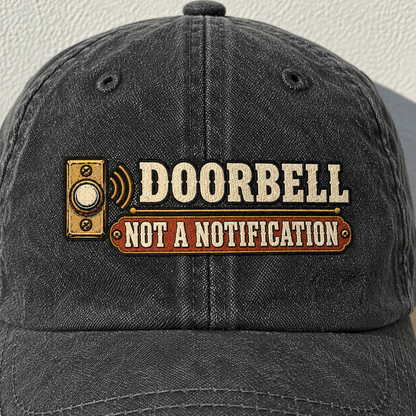 Black vintage washed cap with printed Doorbell Not A Notification slogan, front angle.