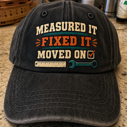 Black vintage washed cap featuring printed “Measured It Fixed It Moved On” slogan, front angle.