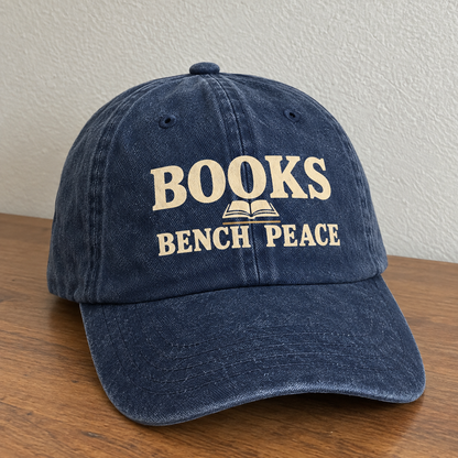Dark blue vintage washed cap with printed Books Bench Peace slogan, angled view.