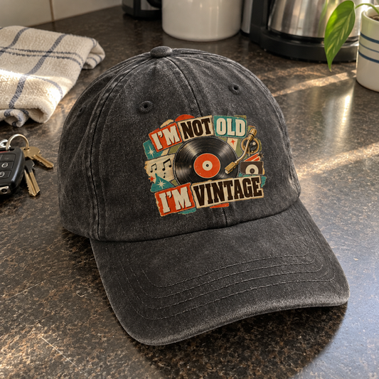 Charcoal vintage washed cap with printed I'm Not Old. I'm Vintage slogan, angled on countertop