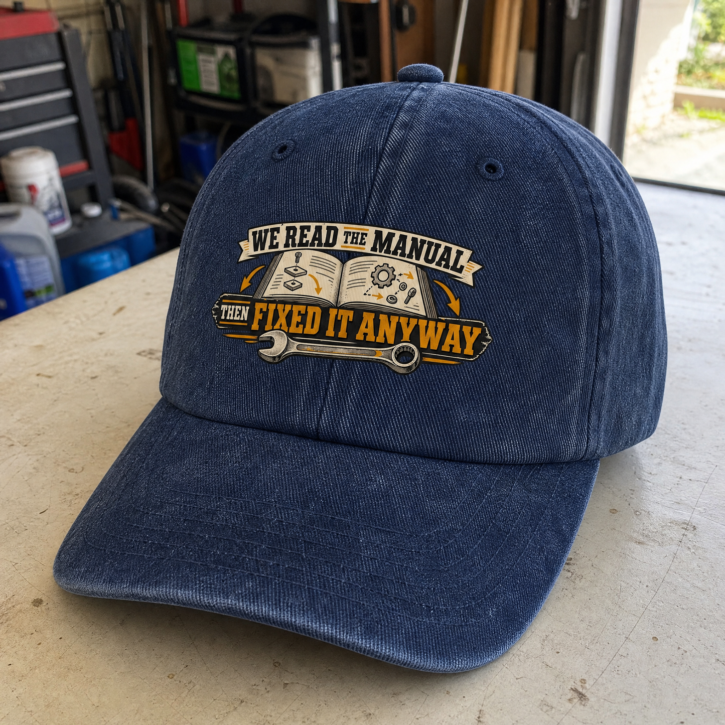 Navy vintage washed cap with printed “We Read The Manual Then Fixed It Anyway” design, angled view