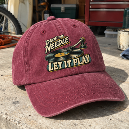 Burgundy vintage washed cap with printed record graphic and Drop The Needle Let It Play slogan, angled view