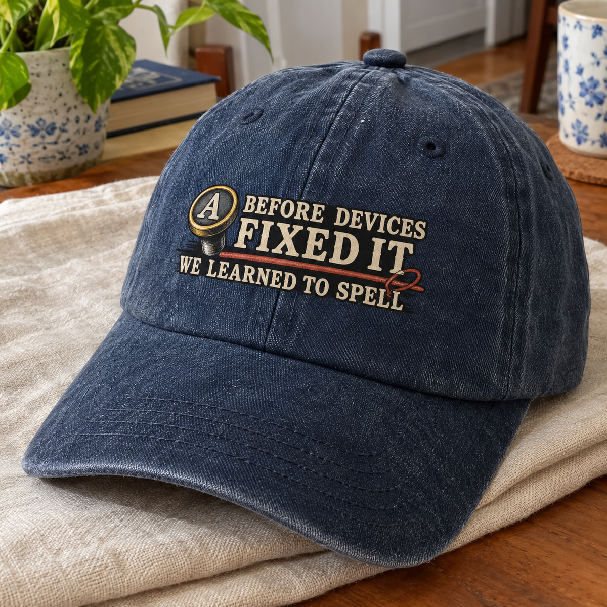 Dark blue vintage washed cap with printed “Before Devices Fixed It” slogan, angled view.