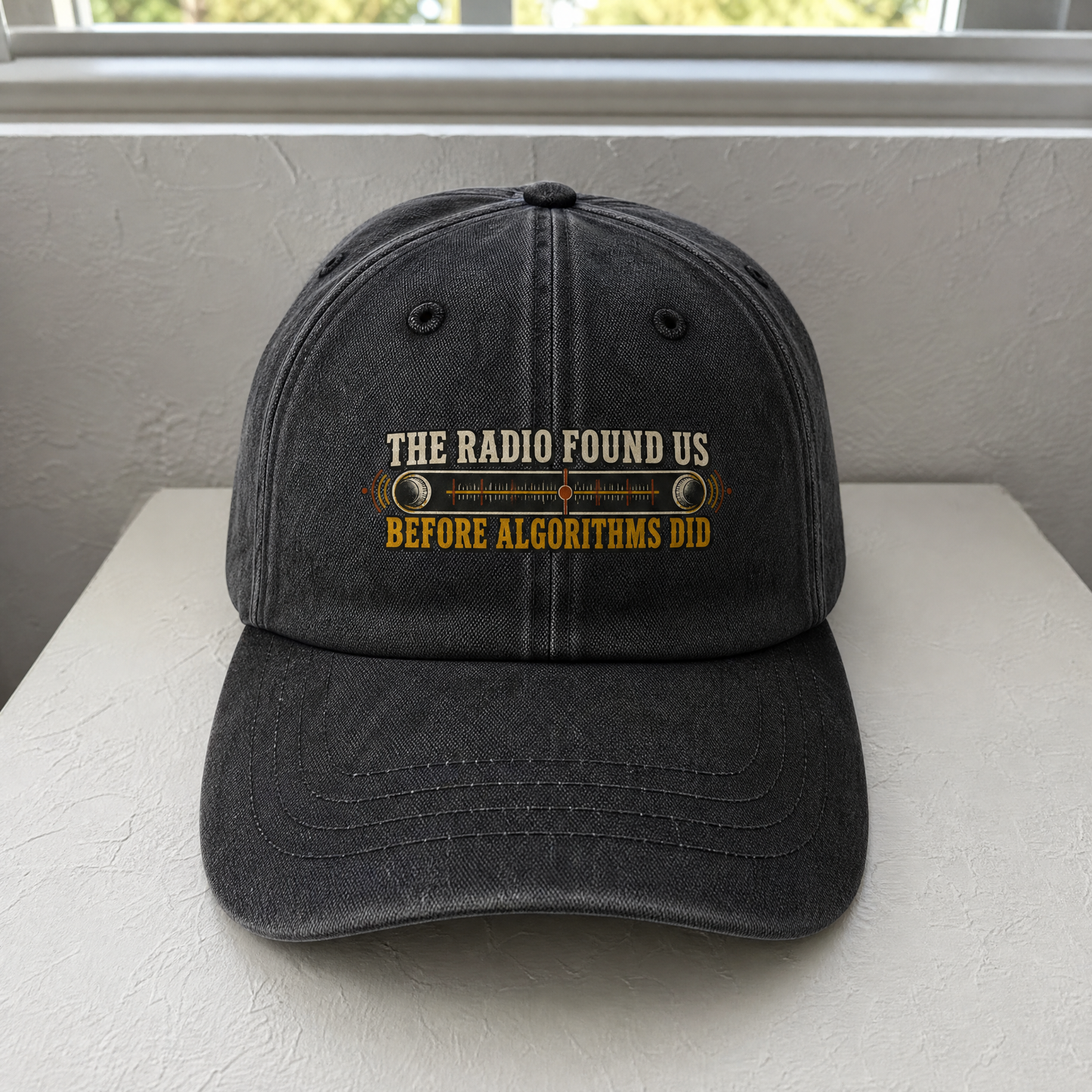 Black vintage washed cap with printed radio slogan, front-facing angle on tabletop.