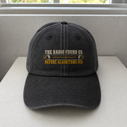 Black vintage washed cap with printed radio slogan, front-facing angle on tabletop.