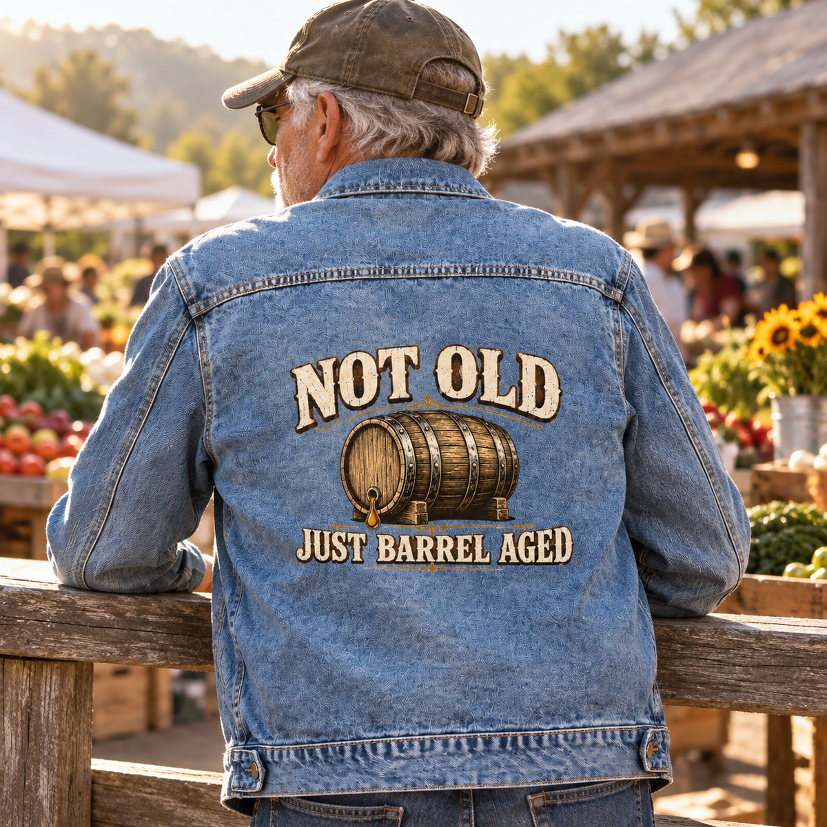 Senior man’s blue vintage denim jacket, back view, printed “Not Old. Just Barrel Aged”