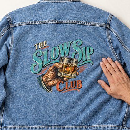Back of blue vintage denim jacket with printed The Slow Sip Club glass design.