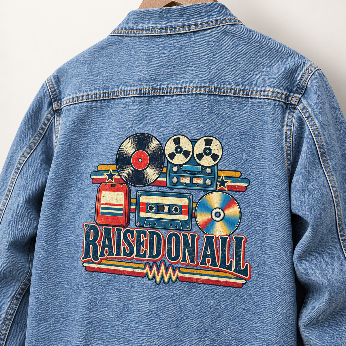 Back view of blue vintage denim jacket with printed retro music graphics and Raised On All slogan