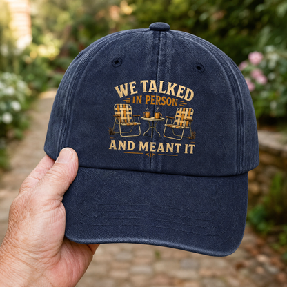 Navy vintage washed cap with “WE TALKED IN PERSON AND MEANT IT” printed design, handheld.