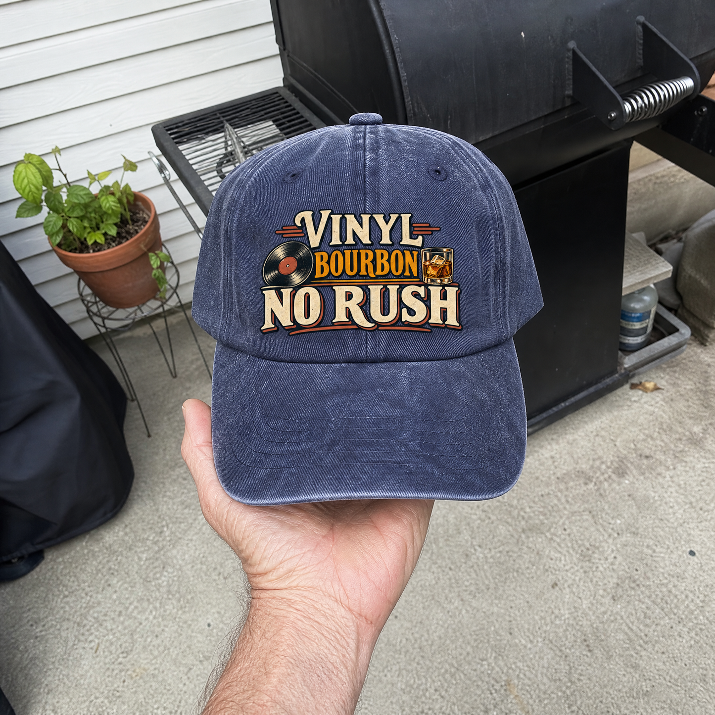 Navy vintage washed cap with printed Vinyl Bourbon No Rush design, handheld outdoors.