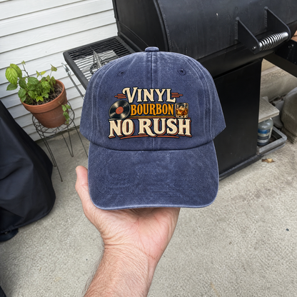 Navy vintage washed cap with printed Vinyl Bourbon No Rush design, handheld outdoors.