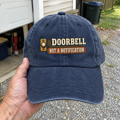Blue vintage washed cap with printed Doorbell. Not A Notification slogan, handheld front view.