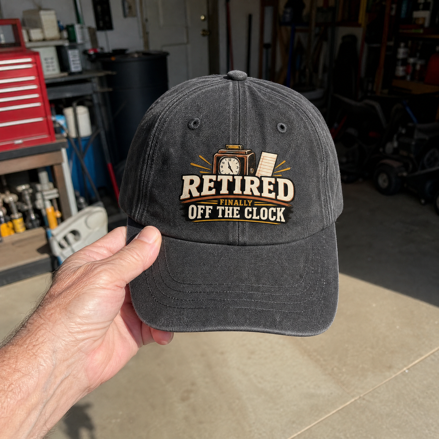 Black vintage washed cap with printed “Retired Finally Off The Clock” slogan, handheld front view.