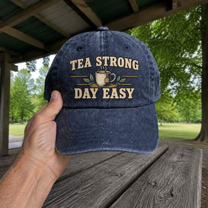 Navy vintage washed cap with printed Tea Strong Day Easy slogan, handheld outdoor view