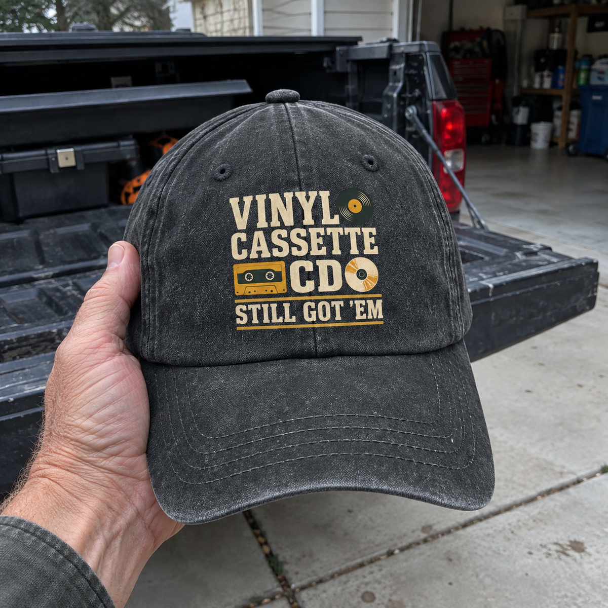 Black vintage washed cap with printed Vinyl Cassette CD Still Got ’Em design, handheld front view