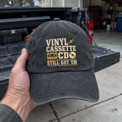 Black vintage washed cap with printed Vinyl Cassette CD Still Got ’Em design, handheld front view