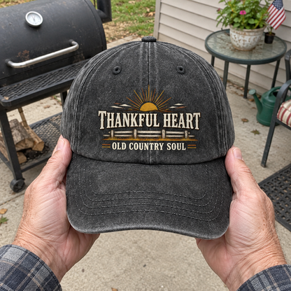Hands holding black vintage washed cap with printed Thankful Heart Old Country Soul design