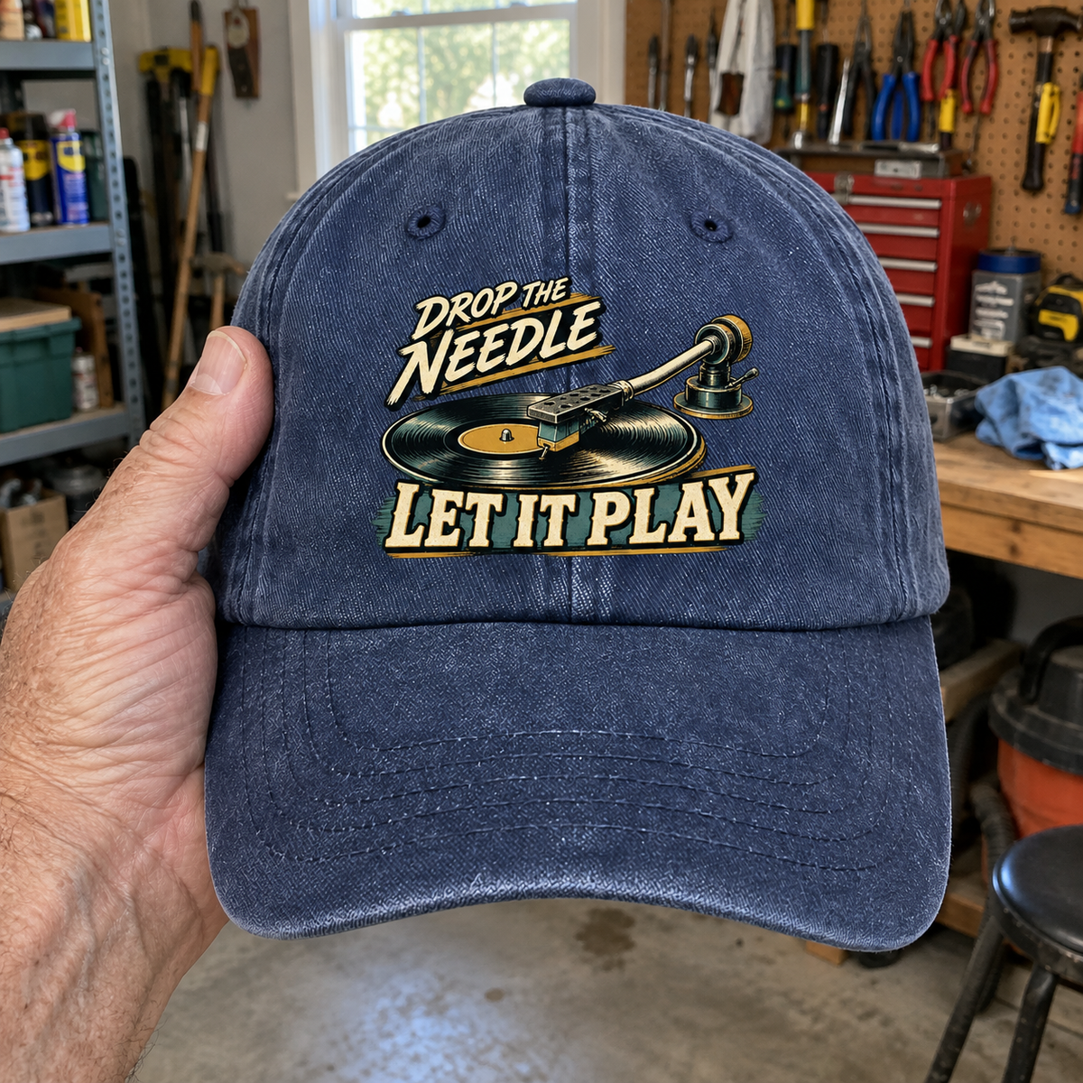 Blue vintage washed cap with printed Drop The Needle. Let It Play record player design, handheld front view