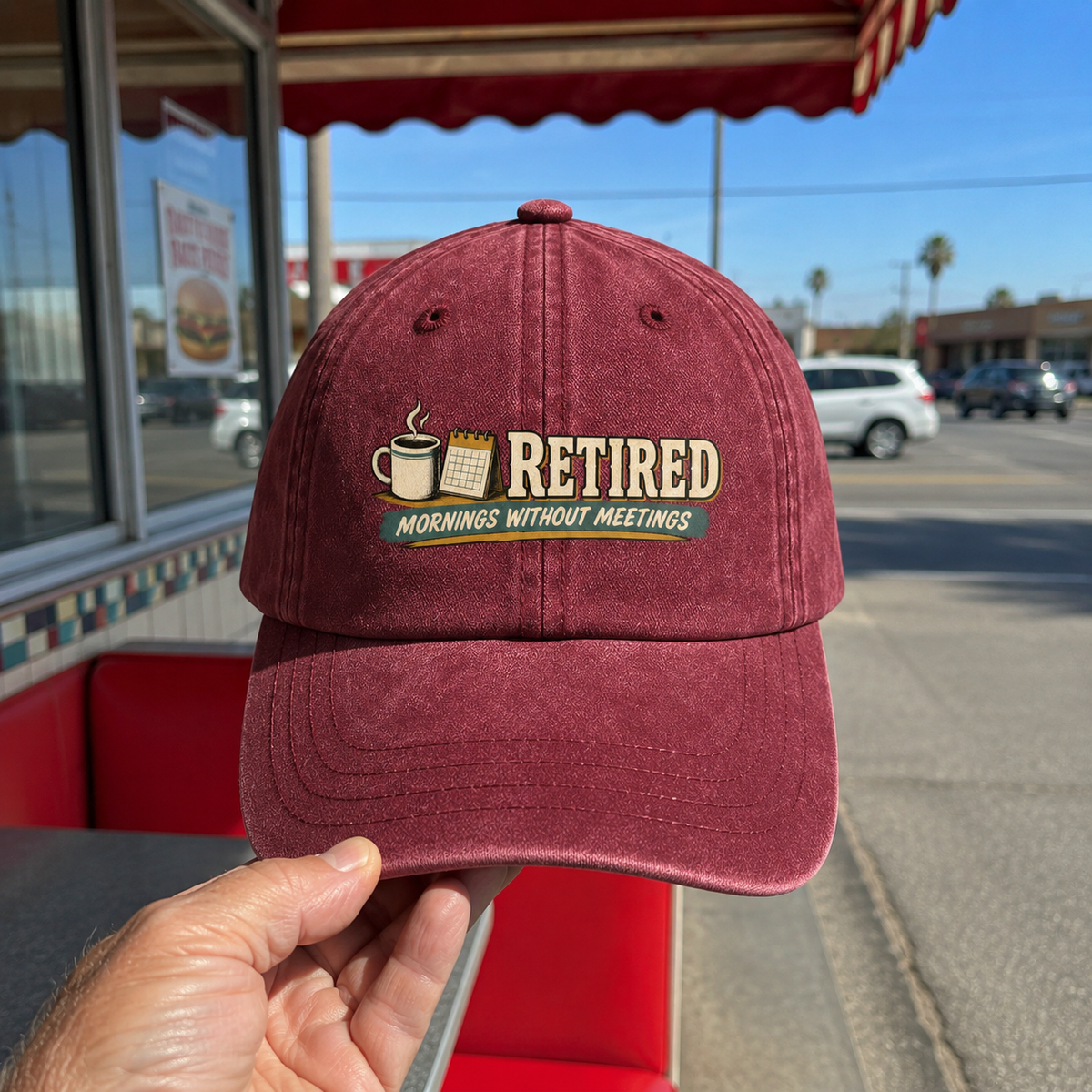 Burgundy vintage washed cap with printed Retired Mornings Without Meetings design, handheld view