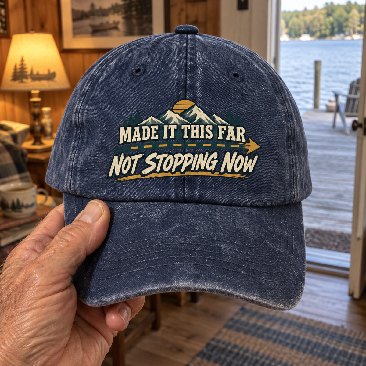 Navy vintage washed cap held by hand, printed Made It This Far Not Stopping Now