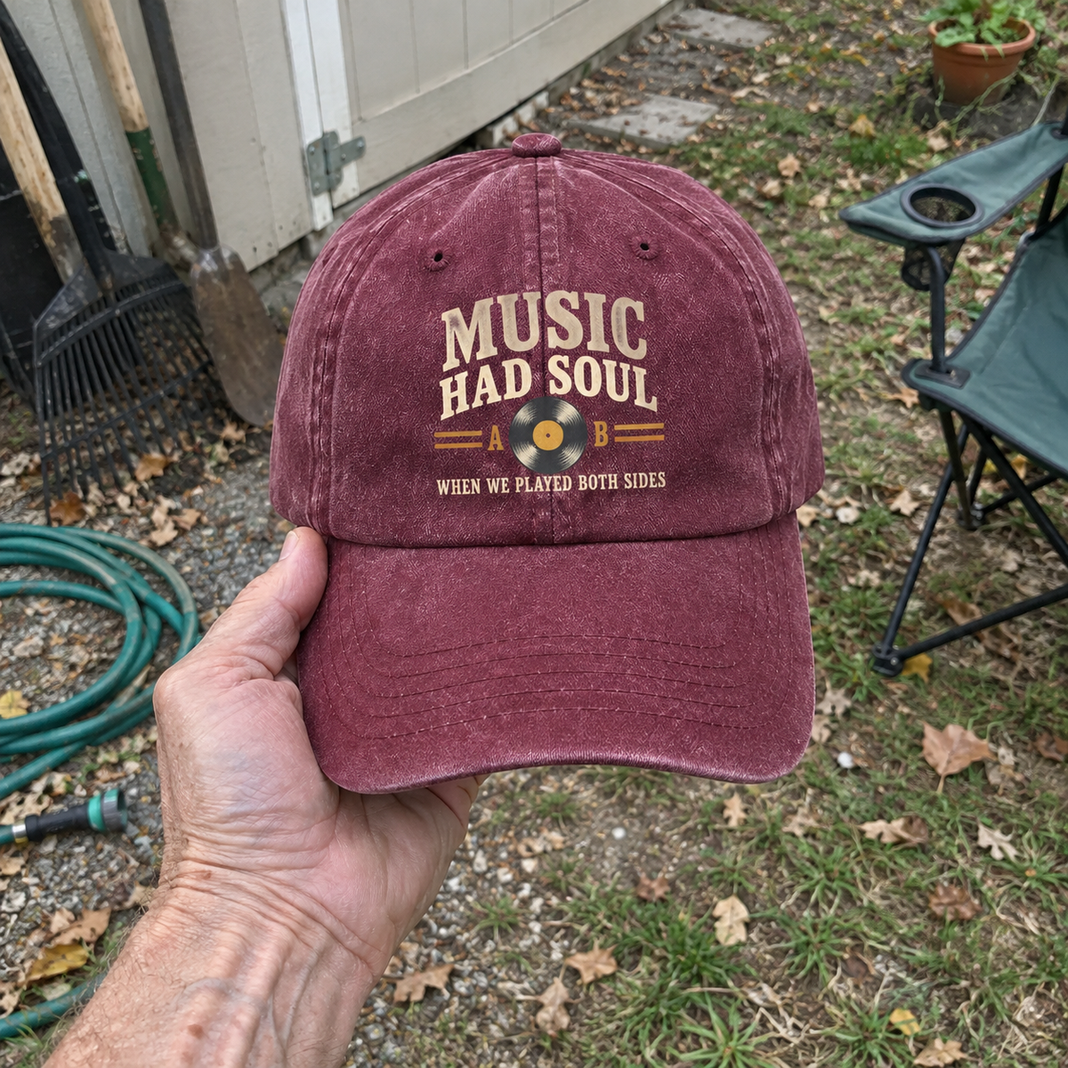 Burgundy vintage washed cap with printed “Music Had Soul” design, handheld outdoors