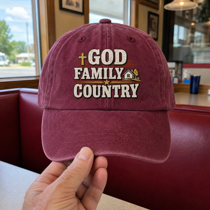 Burgundy vintage washed cap with printed God Family Country slogan, handheld front view.